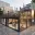 Foto Moderner, zweistöckiger Eventcontainer aus schwarzen Modulen mit großen Glasfronten, Dachterrasse und beleuchtetem Aether-Logo in einer urbanen Umgebung.