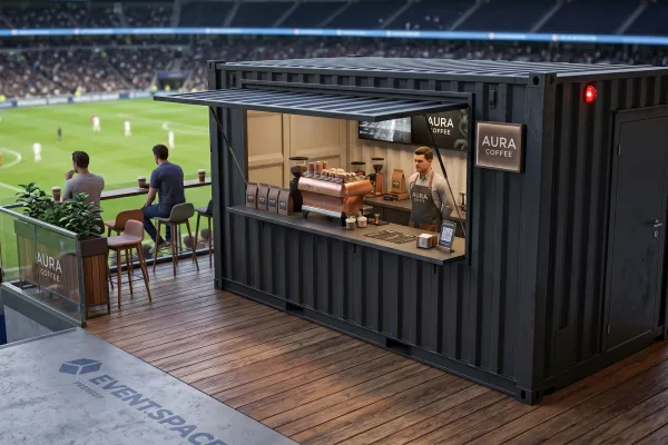 Gastro-Seecontainer „Aura“ für Urban Coffee & Bar - Foto Ein anthrazitfarbener 20-Fuß-Gastro-Seecontainer namens Aura, umgebaut zu einer modernen Kaffeebar mit Holzterrasse in einem Fußballstadion. Ein Barista arbeitet hinter dem Tresen mit einer kupferfarbenen Espressomaschine.