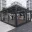 Foto Außenansicht eines modernen, schwarz gerahmten Glascontainers (Showroom) auf einem gepflasterten Stadtplatz, in dem Uhren und Schmuck in Vitrinen präsentiert werden.
